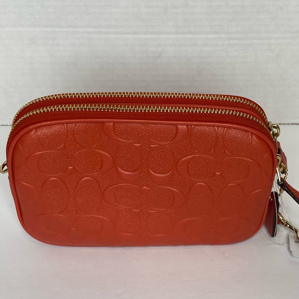 Coach camera bag with signature coated canvas detail. Shoulder/wrist strap.Coral